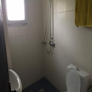 Ein kleines Badezimmer mit Dusche, Toilette und einem Fenster.