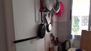 A kitchen with a gas stove, hanging pots, a toaster, and a dish rack. - Residence Fatny (Abidjan)
