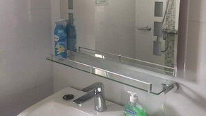 A bathroom with a glass shelf, a sink, and a shower. - Residence Fatny (Abidjan)
