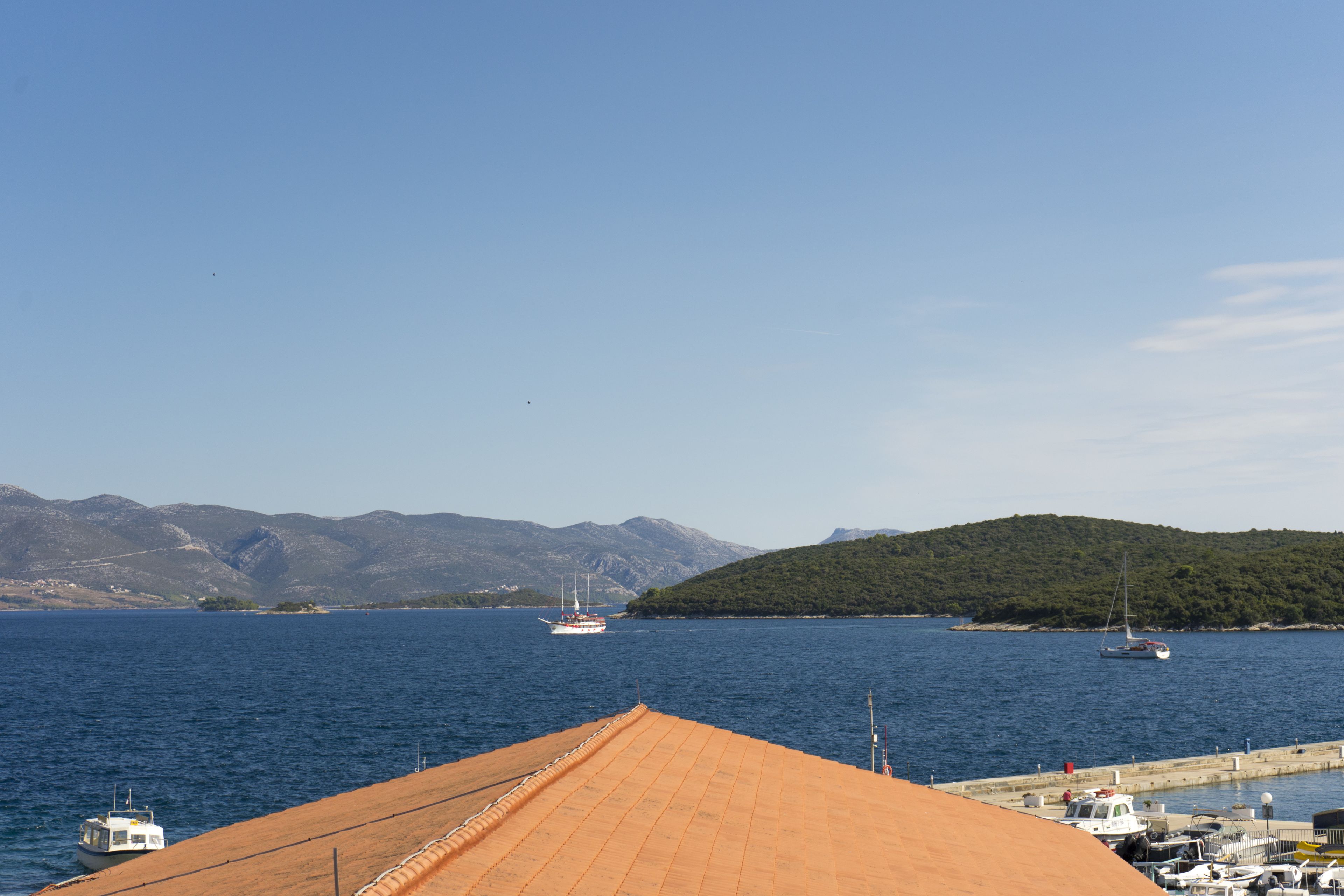A harbor with boats, a dock, and a mountainous backdrop.