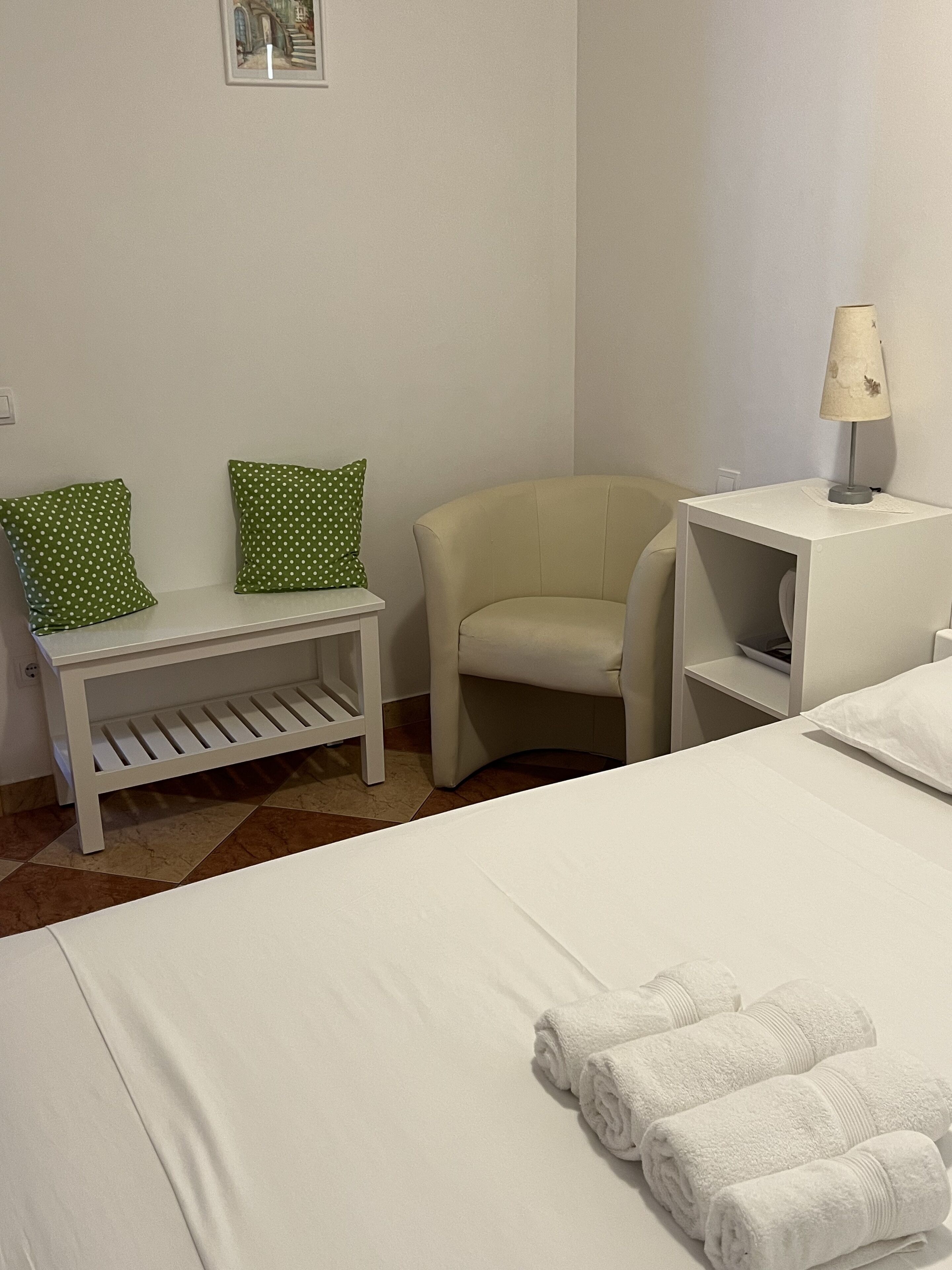 Una habitación de hotel con una cama, una silla, una mesita y una lámpara.
