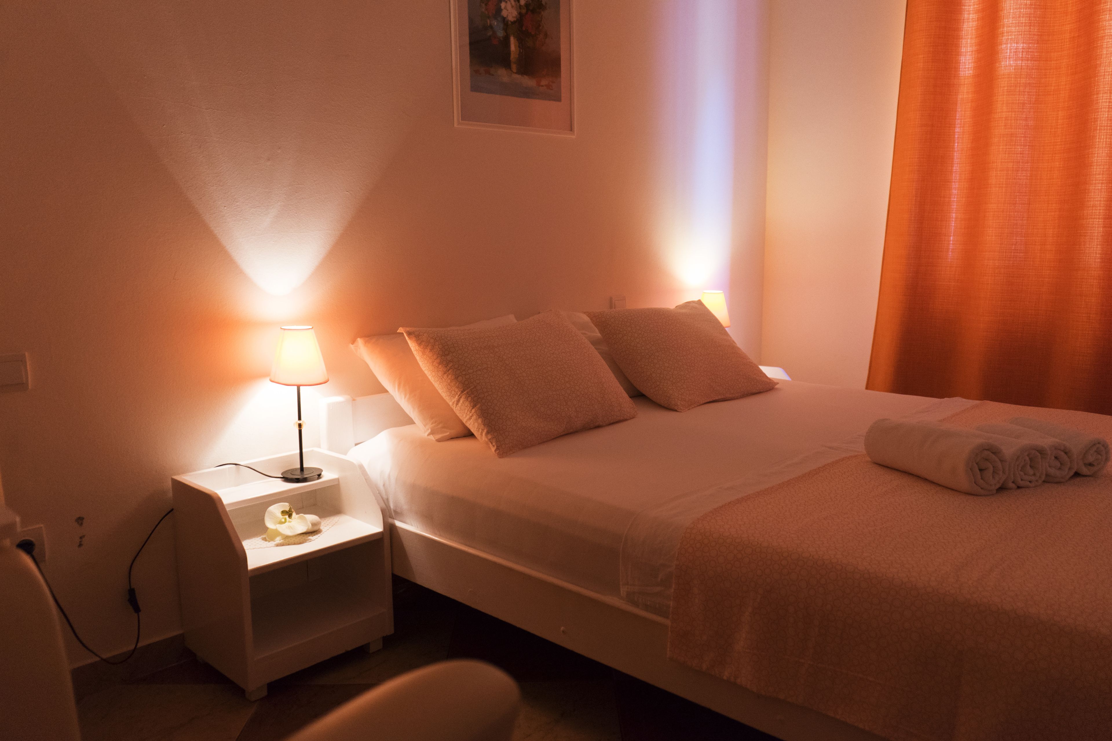 A hotel room with a bed, nightstands, a lamp, and a painting on the wall.