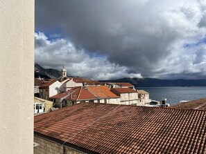 Une ville côtière aux toits recouverts de tuiles en terre cuite, une église imposante dotée d’un clocher et, au loin, un plan d’eau.