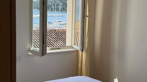 A hotel room with a bed, a window with a view of a marina, and a curtain.