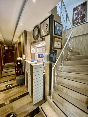 Welcome to our reception area, featuring a digital display, framed artwork, and a staircase leading to the upper floor.