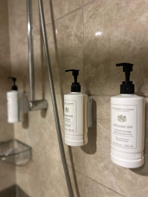 Bathroom features a shower area with a metal shower hose and a small shelf.