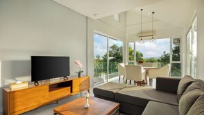 Een moderne woonkamer met een flatscreen televisie, een houten tv-meubel en een grote bank.