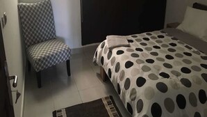 A bedroom with a bed, a chair, a wardrobe, and a window.