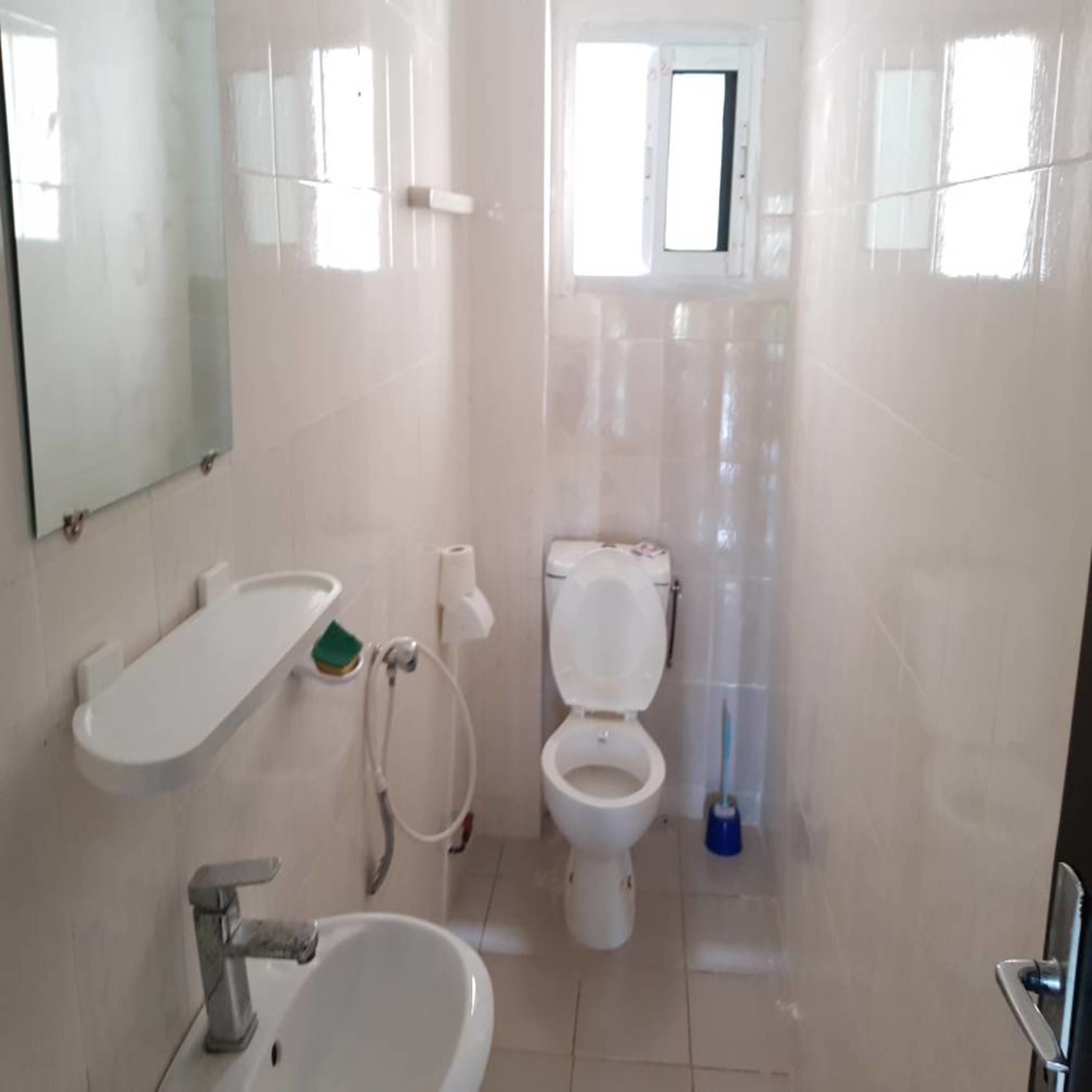 A small, clean bathroom with a toilet, sink, and mirror.