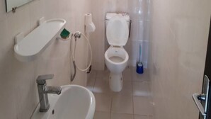 A small, clean bathroom with a toilet, sink, and mirror.