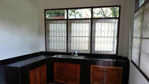 A kitchen with a black countertop, wooden cabinets, a sink, and a window with metal bars.
