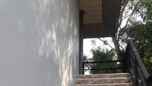 A set of outdoor stone steps leading up to a covered area, with a metal railing on the right.