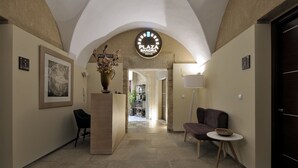 Eine Hotelhalle mit einer Rezeption, einem Blumenstrauß, einem gerahmten Kunstwerk, einer Lampe und einer Sitzecke.