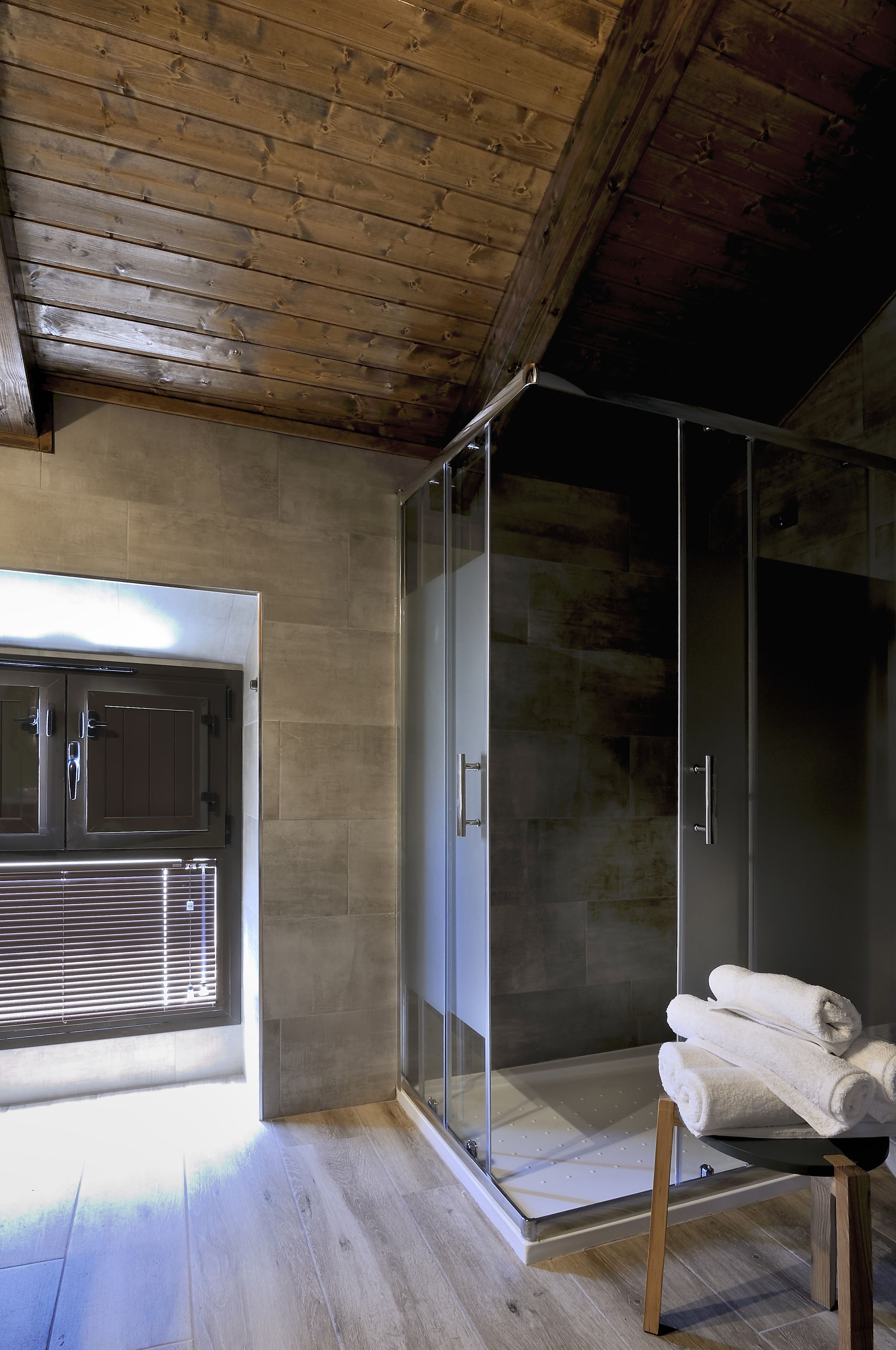 Een moderne badkamer met een glazen douche, houten vloer en een handdoekrek.
