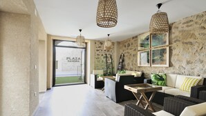 Ein geräumiges Wohnzimmer mit Rattanmöbeln, einer Steinwand und Blick ins Freie.