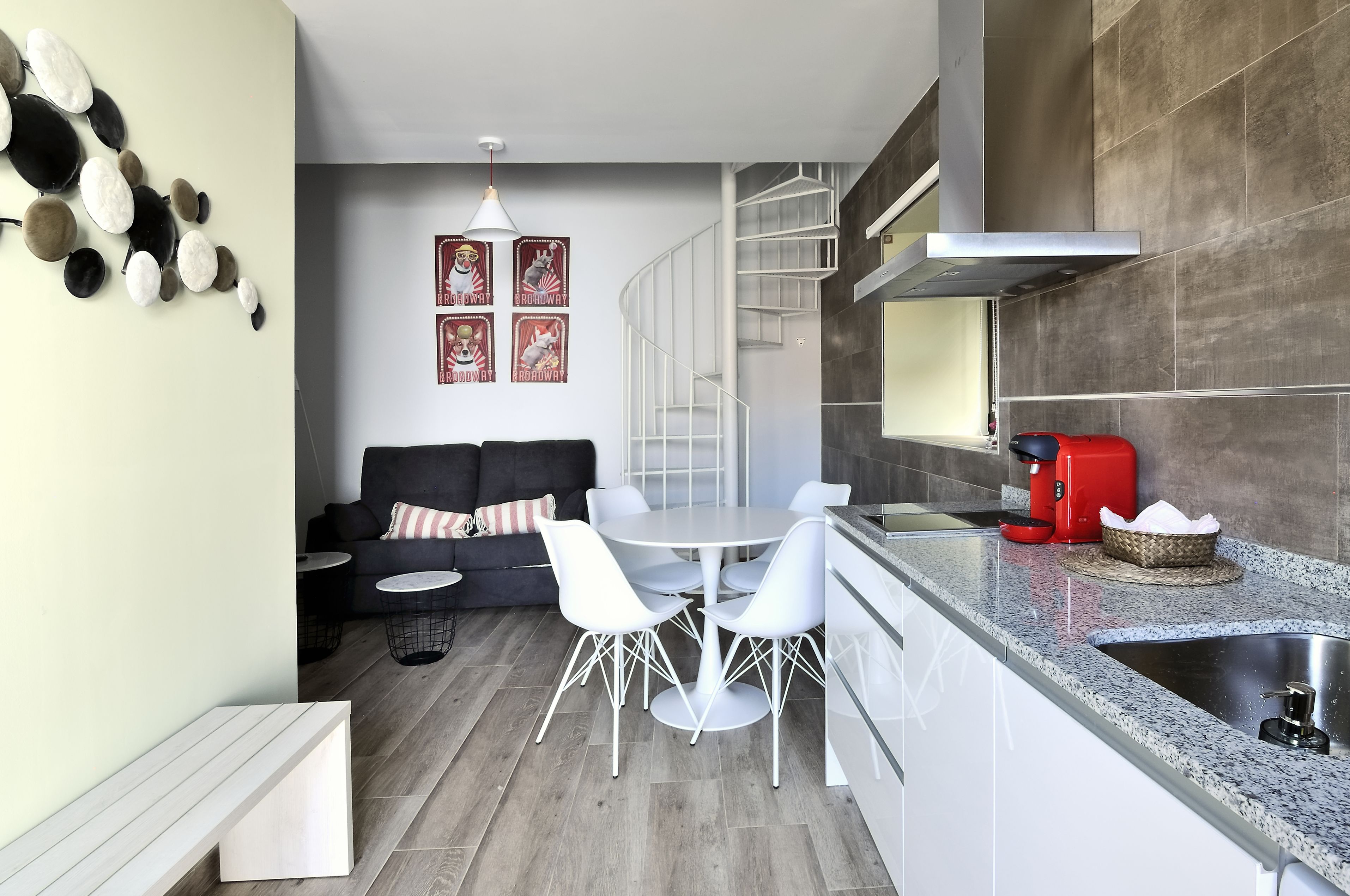 Eine moderne Küche mit Essbereich, einer Treppe und einem Sofa.