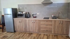 Cozinha equipada com frigorífico, micro-ondas, torradeira, chaleira, lava-loiça e armários de madeira.