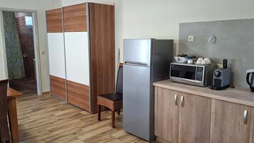 Cocina compacta con refrigerador, microondas y cafetera sobre la encimera.