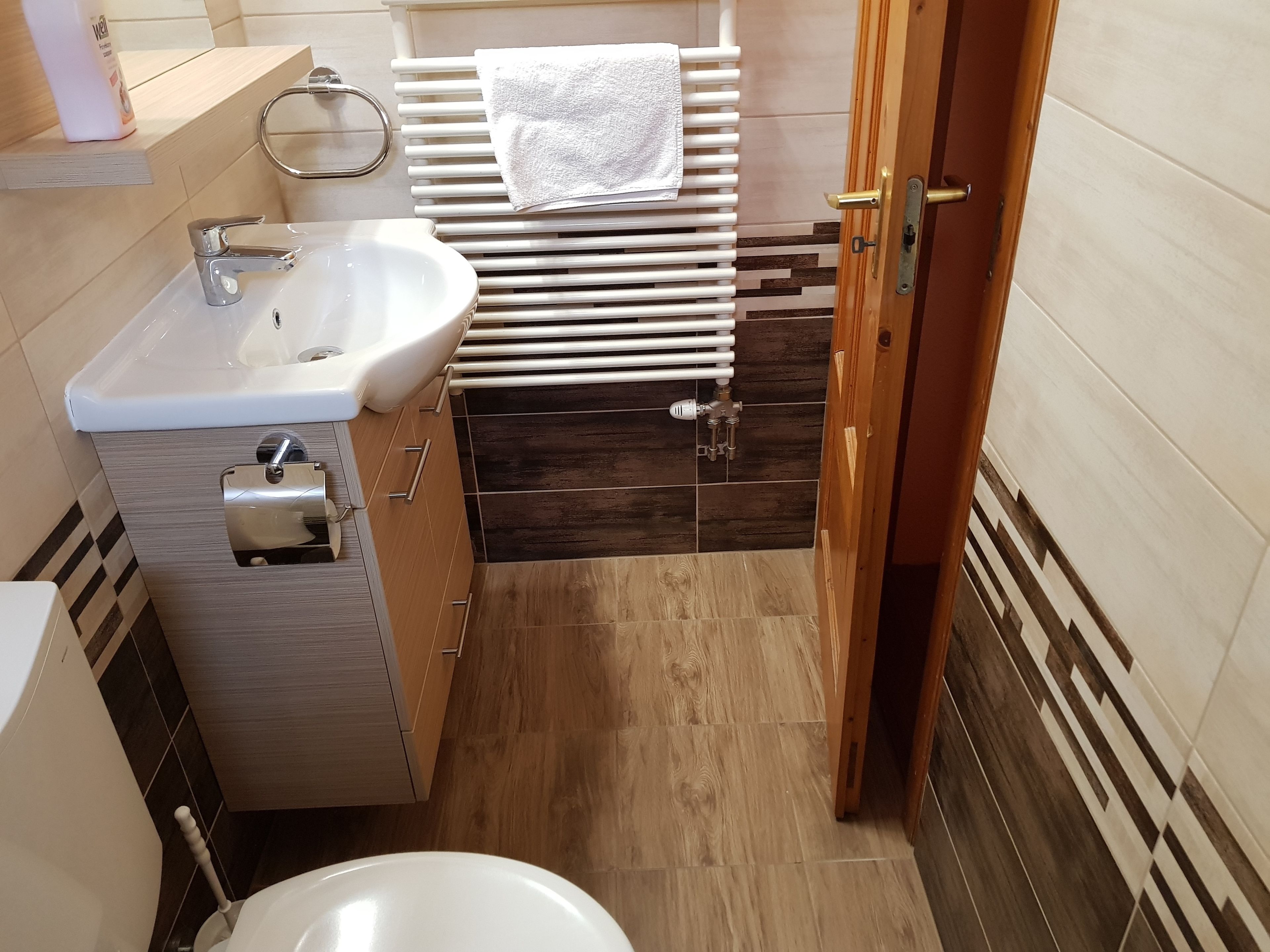 A compact bathroom with a sink, toilet, and a towel rack.