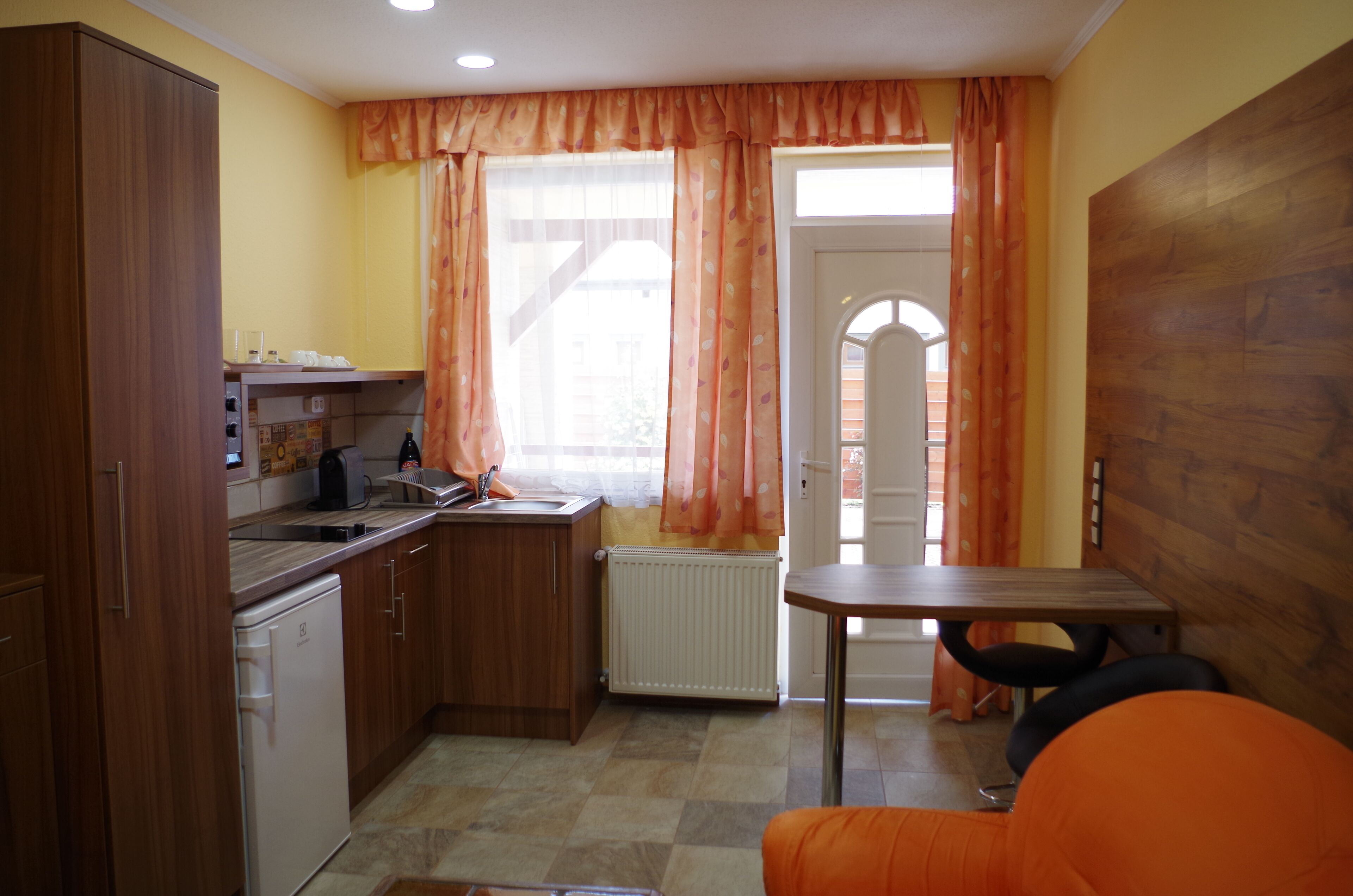 A compact kitchen with wooden cabinets, a built-in oven, and a small dining table.