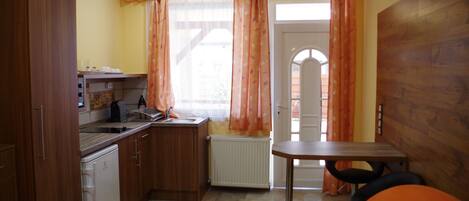 A compact kitchen with wooden cabinets, a built-in oven, and a small dining table.