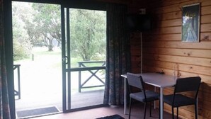 Une cabane en bois comprenant un coin repas, un canapé et un téléviseur fixé au mur.