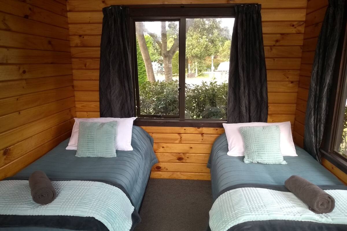 Une cabine équipée de deux lits, chacun avec un oreiller et une serviette enroulée.