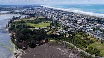 Vista aérea de un pueblo costero con playa, zona residencial y un extenso campo abierto.