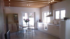 A spacious kitchen with white cabinets, a dining table with chairs, and a refrigerator. - New Kertzfeld cottage, luxury performance in Alsace countryside. (Kertzfeld)