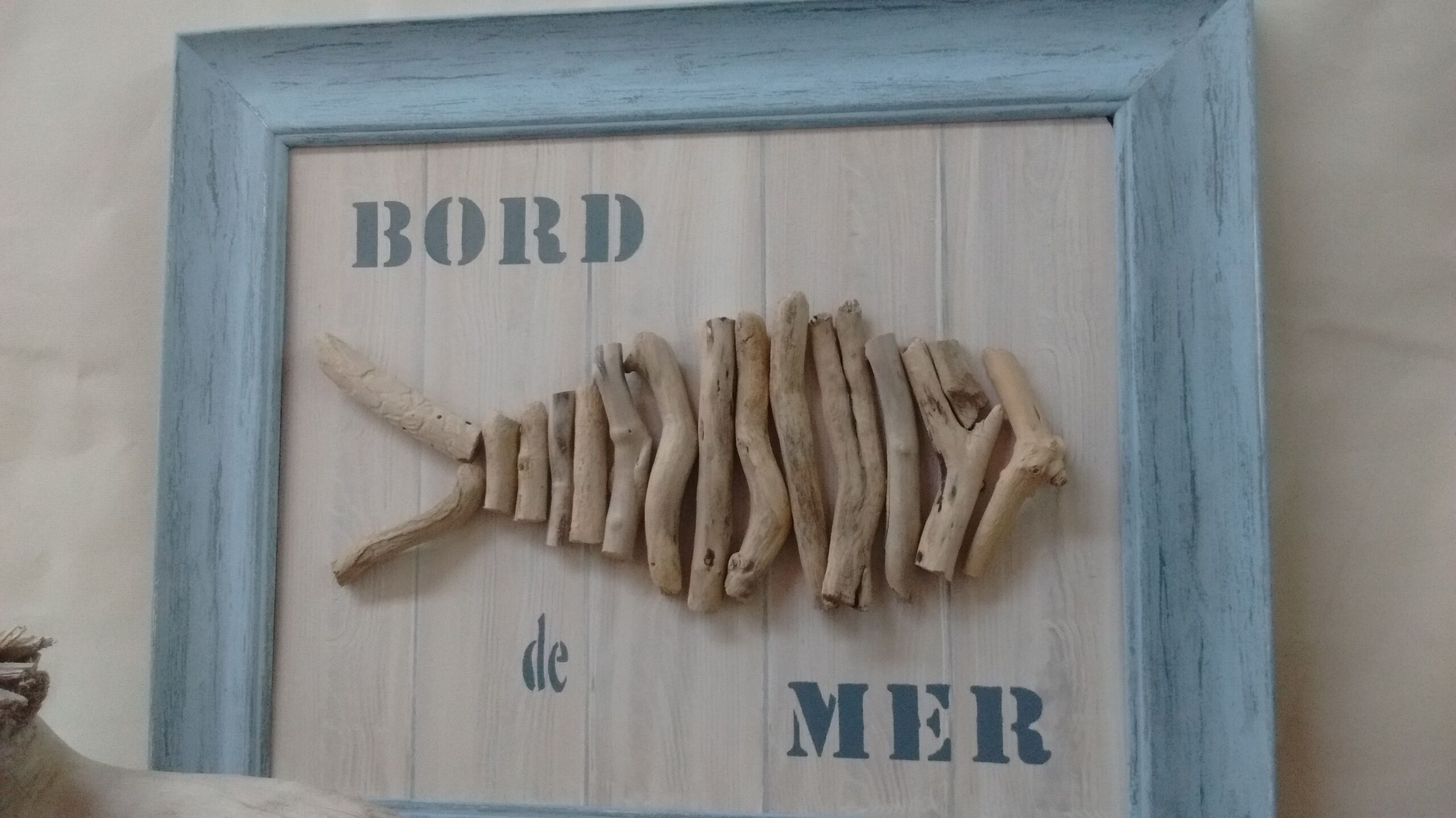 Ein gerahmtes Holzmodell eines Fischskeletts mit der Aufschrift 'BORD de MER'.
