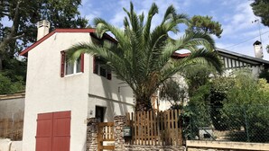 A two-story house with a red door and a stone wall. - Town house ideal for a couple with children (Arcachon)
