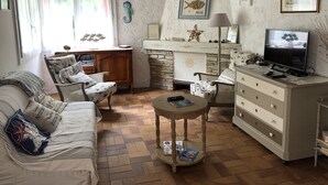 A cozy living room with a sofa, a coffee table, a TV, and a fireplace. - Town house ideal for a couple with children (Arcachon)