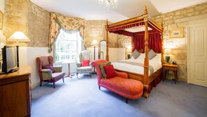 A traditional four-poster bed with a canopy, a stone wall, a chandelier, and a view of the outdoors through a window. - OYO Bailbrook Lodge, Bath (Bath)