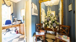 A room with a desk, computer, chair, and a large mirror with a floral arrangement. - OYO Bailbrook Lodge, Bath (Bath)