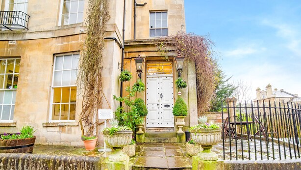 A historic building with a traditional entrance, steps leading up to a door, and potted plants at the base. - OYO Bailbrook Lodge, Bath (Bath)
