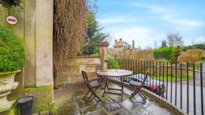 A stone patio with a table and chairs, a black car parked nearby, and a sign reading "OYO". - OYO Bailbrook Lodge, Bath (Bath)