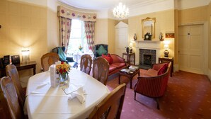 A well-appointed hotel room with a dining area, a fireplace, and a chandelier. - OYO Bailbrook Lodge, Bath (Bath)