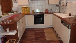 A compact kitchen with white cabinets, a stove, a sink, and a dishwasher. There is a wooden countertop and a patterned rug on the floor. - CENTRE HISTORIQUE MAUSSANE, house 72 m2 with fenced garden,  (Maussane les alpilles)