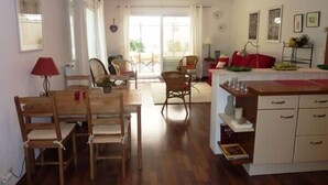 A spacious kitchen with wooden furniture, a dining area with chairs, and a view through a glass door to an outdoor patio. - CENTRE HISTORIQUE MAUSSANE, house 72 m2 with fenced garden,  (Maussane les alpilles)