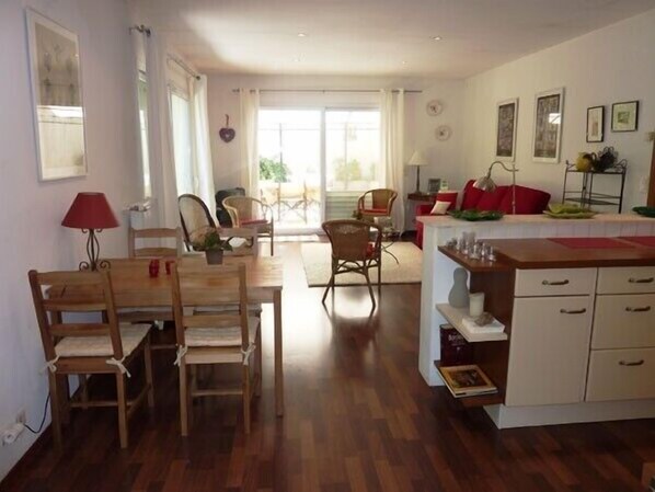 A spacious kitchen with wooden furniture, a dining area with chairs, and a view through a glass door to an outdoor patio.