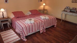 A bedroom with two beds, a bedside table with a lamp, a small desk with a lamp, and a wall-mounted picture frame. - CENTRE HISTORIQUE MAUSSANE, house 72 m2 with fenced garden,  (Maussane les alpilles)