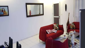 A modern living room with a red sofa, a glass coffee table, and a dining area with chairs and a table. - Residence Cécilia (Abidjan)