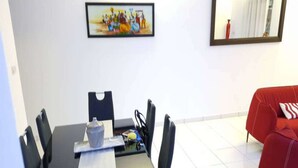 A dining area with a table, chairs, and a painting on the wall. - Residence Cécilia (Abidjan)