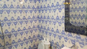 A bathroom with a wave pattern tile design, a toilet, a sink, and a mirror. - Résidence Esther 2 (Abidjan)