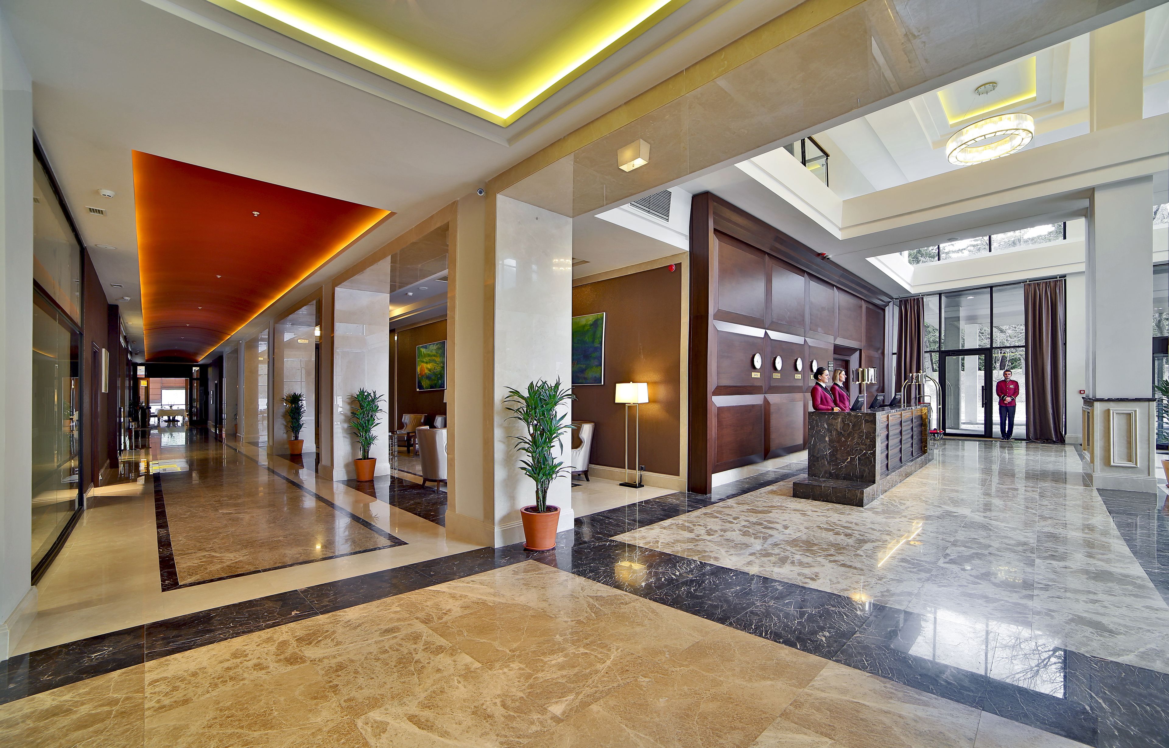 A spacious lobby with a high ceiling, marble flooring, and a reception desk.