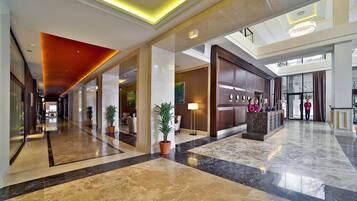 A spacious lobby with a high ceiling, marble flooring, and a reception desk.
