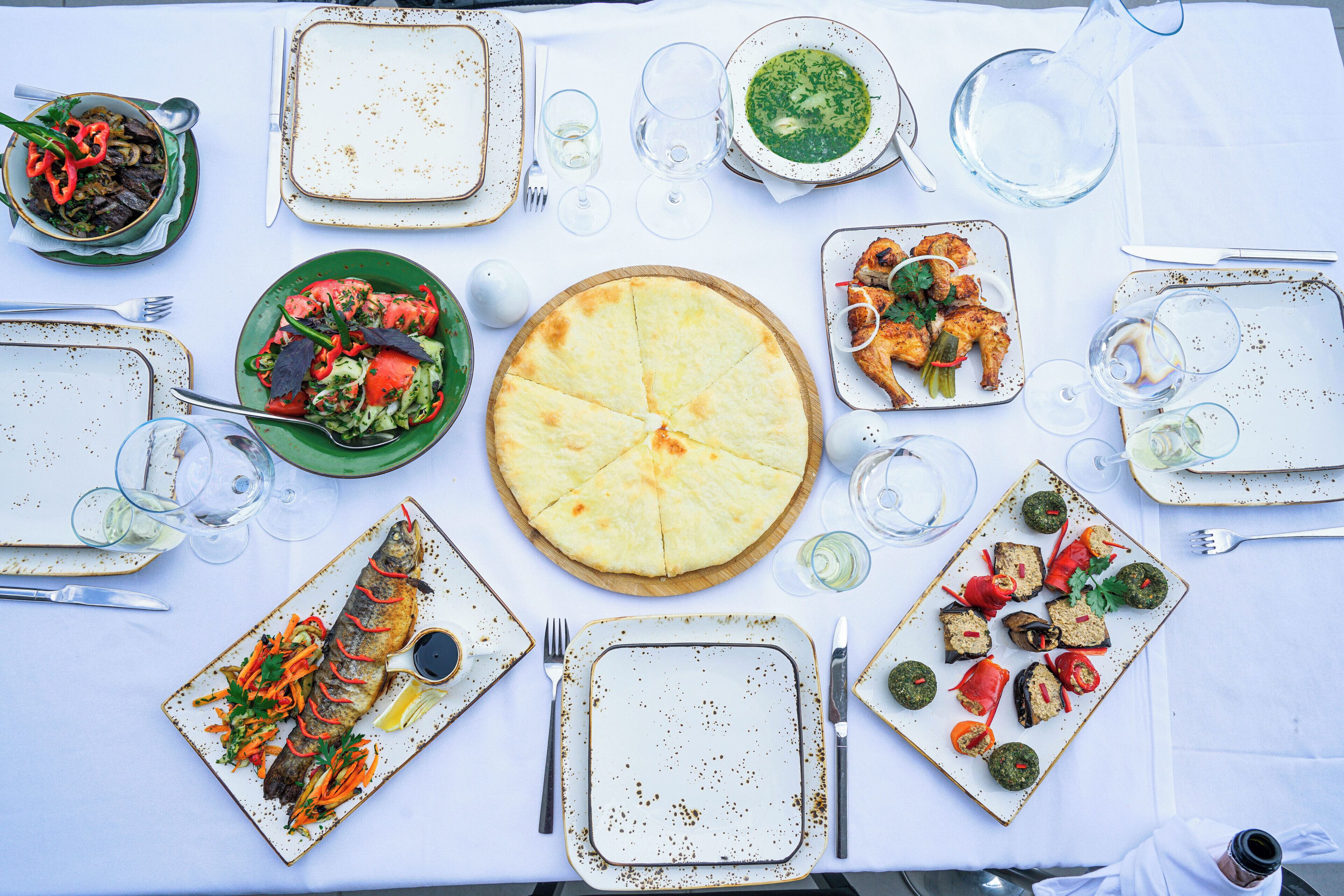 Une table mise pour un repas, avec différents plats, des verres et des couverts.
