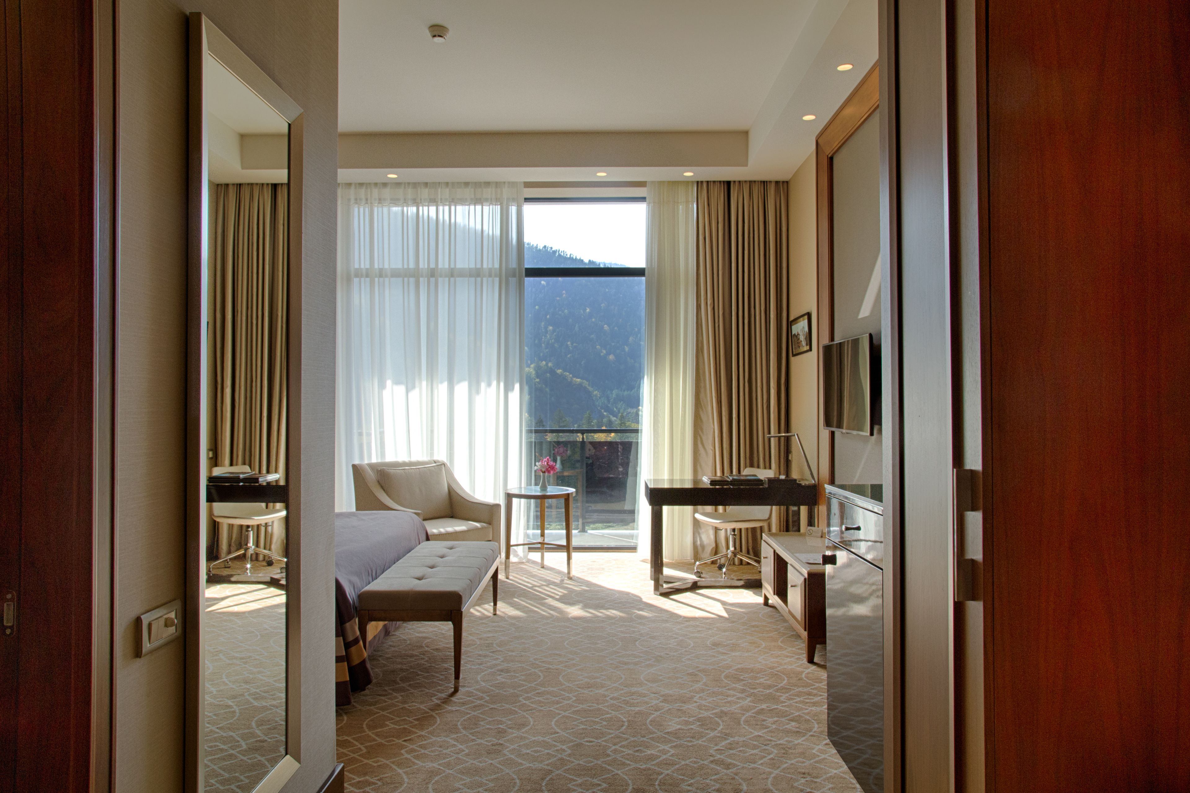Habitación de hotel con cama, escritorio, silla, mesita y televisor.