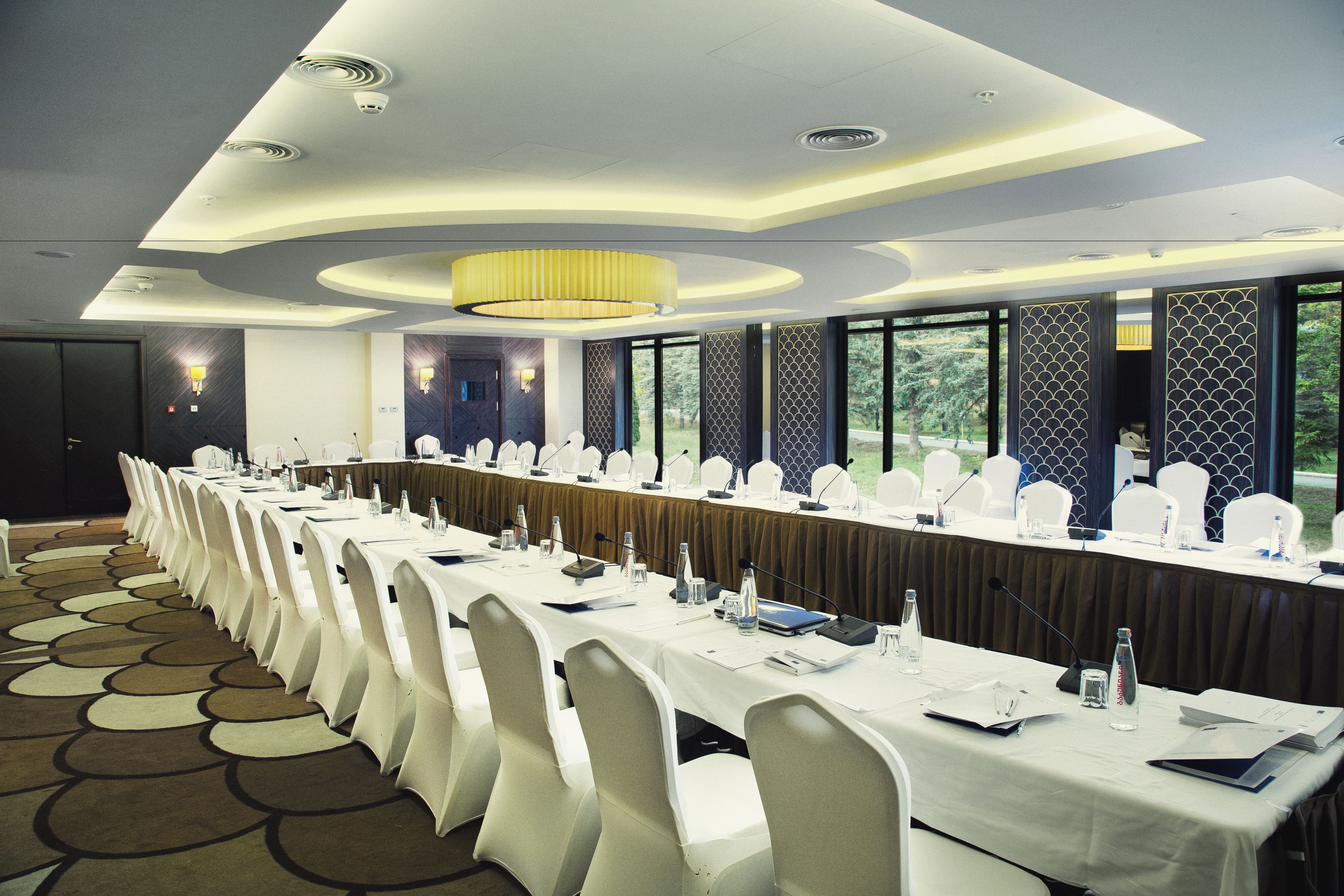 A conference room with a long table, white chairs, and a chandelier.