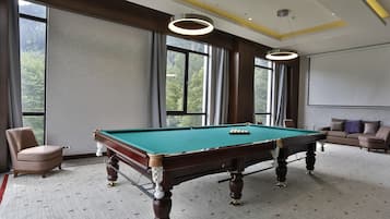 Una mesa de billar con superficie de fieltro verde, una vara de billar y una silla.